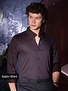 Man in a dark satin shirt posing indoors.