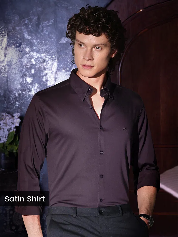 Man in a dark satin shirt posing indoors.
