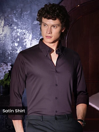 Man in a dark satin shirt posing indoors.