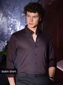 Man in a dark satin shirt posing indoors.