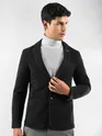Man in a mens black blazer, with white turtleneck sweater, and grey trousers