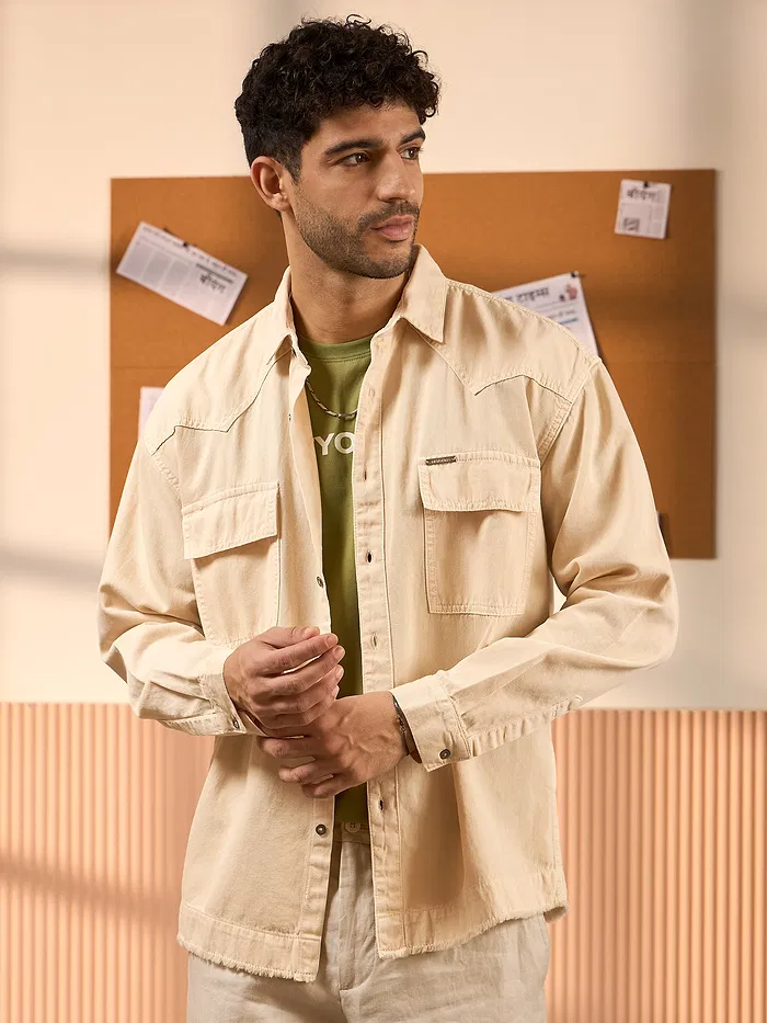 Cream denim shirt for mens with flap pockets, styled over a green t-shirt.