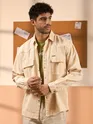 Cream denim shirt for mens with flap pockets, styled over a green t-shirt.