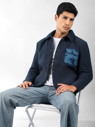 navy blue mens stylish winter jacket with satin pocket and light blue jeans seated on a chair.