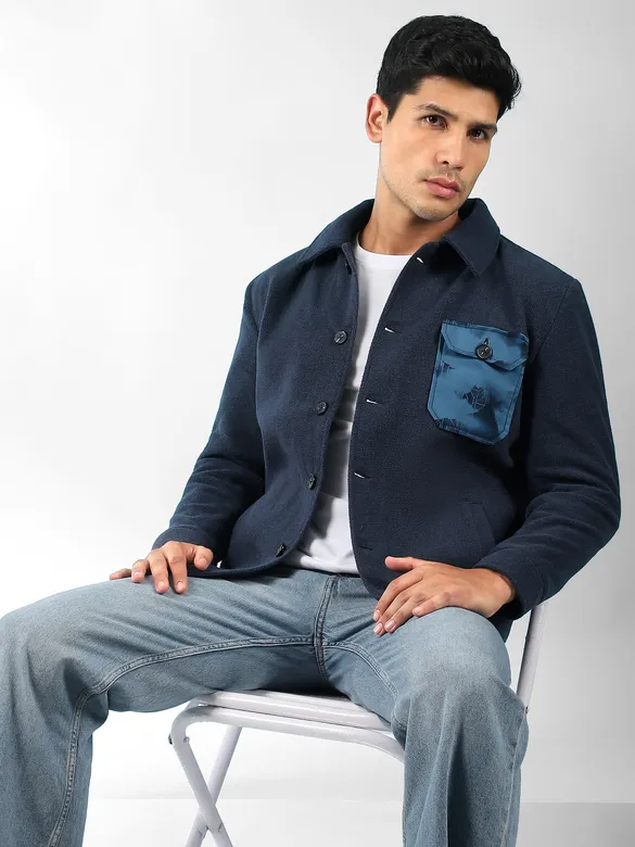navy blue mens stylish winter jacket with satin pocket and light blue jeans seated on a chair.