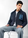 navy blue mens stylish winter jacket with satin pocket and light blue jeans seated on a chair.