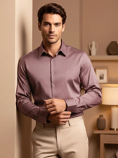 Man in a Mauve pink shining shirts with black trousers, posing against a red textured wall.
